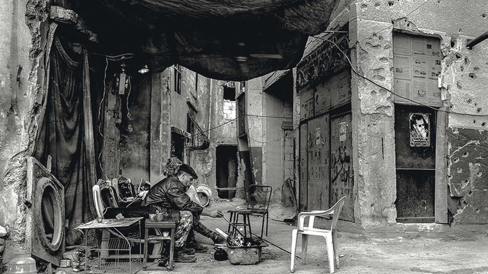 Un par de soldados cocinan sobre unas brasas en una zona de la capital donde se ven los agujeros de los tiroteos y las casas abandonadas.