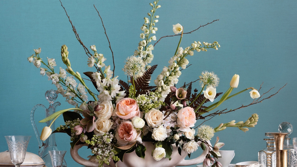 Arreglo floral, inspirado en Rungstedlund, compuesto por diferentes tipos de rosas, lilas, nardos y tulipanes, entre otras flores. También lleva hojas de magnolio y helecho, y ramas de cerezo. El jarrón es un diseño de Constance Spry editado por Loewe.